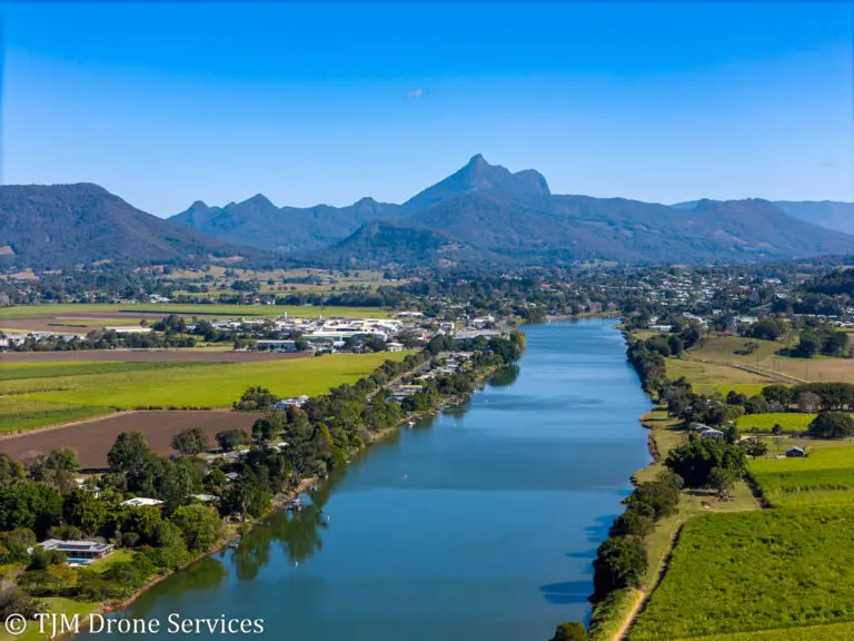 A mountain in the background overlooking pictureseque farmland and a river showcasing drone photography and drone video, drone landscape photography